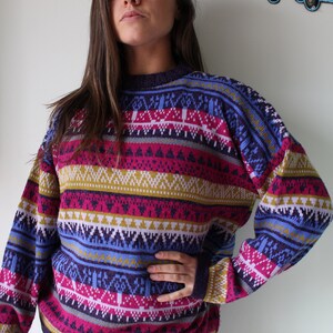 Puede incluir: Un su&eacute;ter de rayas coloridas con un patr&oacute;n geom&eacute;trico en tonos de morado, rosa, azul, amarillo y blanco.