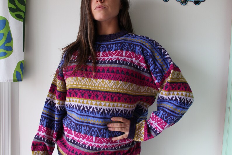 Puede incluir: Un su&eacute;ter de rayas coloridas con un patr&oacute;n geom&eacute;trico en tonos de morado, rosa, azul, amarillo y blanco.