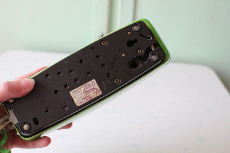 May include: The bottom of a green rotary phone with a black dial and a label that reads "2X200/100".