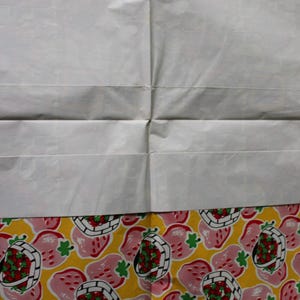 May include: A white sheet of paper with a yellow and pink border. The border has a repeating pattern of pink strawberries with green leaves and red centers in a white basket on a yellow background.