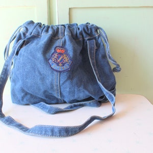 May include: A blue denim drawstring bag with a blue, red, and gold embroidered logo that says "G.I.L.A.R.D."