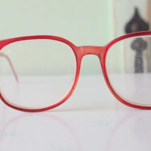 May include: Red plastic framed spectacles with round lenses.