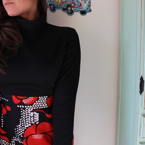Peut inclure: Robe noire &agrave; manches longues avec un col montant et une jupe &agrave; motifs. La jupe pr&eacute;sente un fond noir avec des motifs floraux rouges et des pois blancs. La robe est de style vintage.