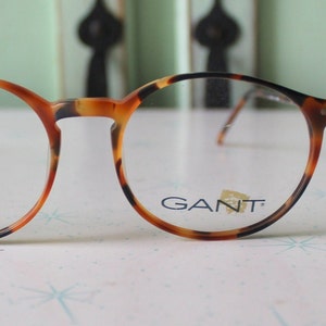 May include: Tortoise shell round eyeglasses with a GANT logo on the right lens.