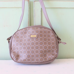 May include: A brown shoulder bag with a gold-colored metal clasp and a patterned design. The bag has a strap and a small tag that says "GITANO 1".