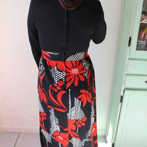 Peut inclure: Robe noire vintage avec un haut &agrave; manches longues et une jupe &agrave; imprim&eacute; floral. La jupe pr&eacute;sente un motif audacieux de fleurs rouges et d'accents blancs sur fond noir. La robe a un col montant et un corsage ajust&eacute;.