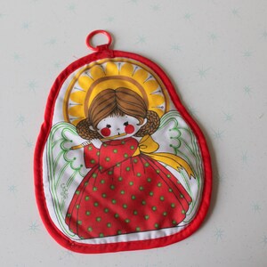 May include: A red and white oven mitt with a cartoon angel design. The angel wears a red dress with green polka dots and a yellow bow. The mitt has a red trim and a loop for hanging.