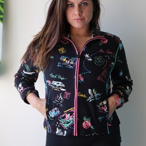 May include: Black zip-up jacket with a colorful print of travel-themed illustrations, including a road trip, a map, and the words "Be Happy".