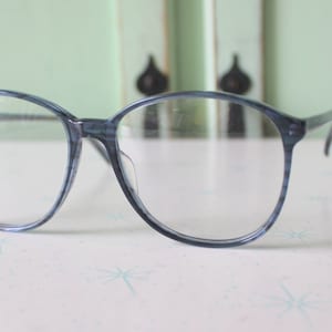 Puede incluir: Gafas de plástico azul con montura redonda.