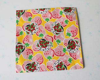 May include: Yellow fabric with a repeating pattern of pink strawberries in baskets. The strawberries are red with green leaves and the baskets are white with black outlines.
