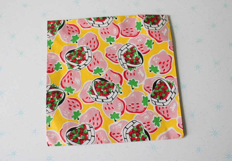 May include: Yellow fabric with a repeating pattern of pink strawberries in baskets. The strawberries are red with green leaves and the baskets are white with black outlines.