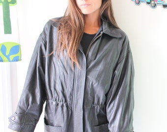 Könnte beinhalten: Eine schwarze Lederjacke mit Reißverschluss und Kordelzug in der Taille. Die Jacke hat lange Ärmel und zwei Taschen.