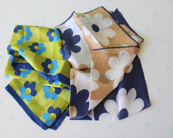 May include: Two silk scarves with floral patterns. One scarf is green with blue flowers and a chequered pattern. The other scarf is beige with white flowers and a navy blue border.
