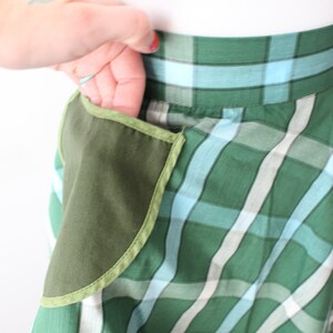 Pode incluir: Uma saia xadrez verde e azul com um grande bolso verde na lateral.