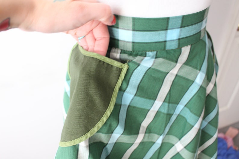 Pode incluir: Uma saia xadrez verde e azul com um grande bolso verde na lateral.