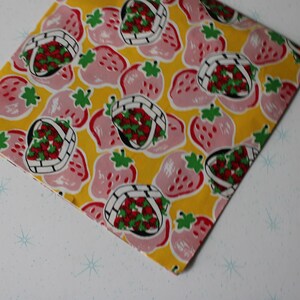 May include: A yellow fabric with a pink and red strawberry print. The strawberries are in baskets and some are whole.