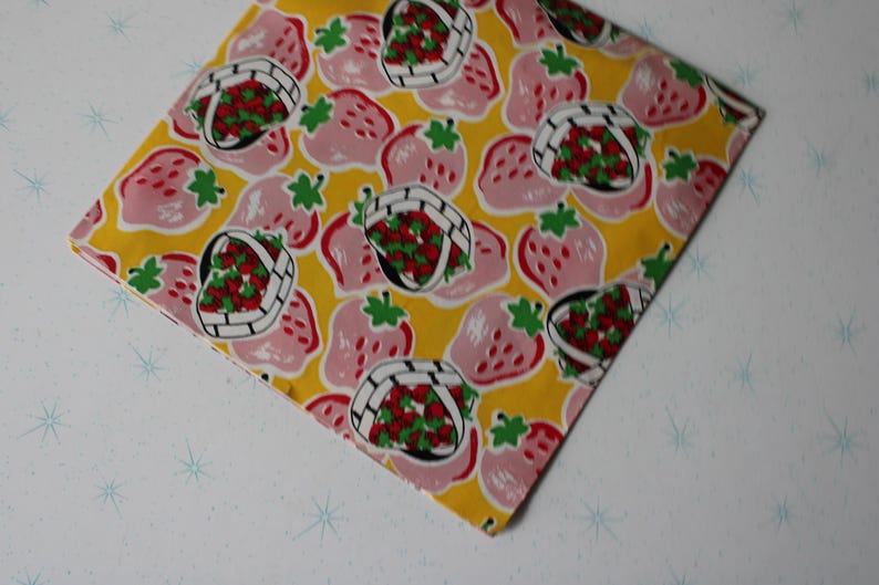 May include: A yellow fabric with a pink and red strawberry print. The strawberries are in baskets and some are whole.