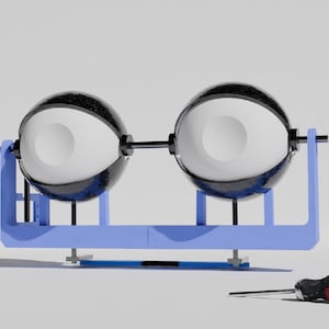 May include: Two black and white spheres are connected by a black rod and mounted on a light blue frame. A red and black screwdriver rests on the white surface in front of the frame.