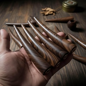 May include: Several handcrafted wooden smoking pipes with a dark brown finish and a tapered design. The pipes are held in a hand, with others visible in the background. The wood grain is prominent, and the pipes have a smooth, polished appearance.