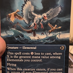 May include: A Magic: The Gathering card titled "Sunderflock" featuring a creature with large wings and a duck-like appearance, flying over water. The card has a blue background with text describing the creature's abilities. The card's power and toughness are 5/5.