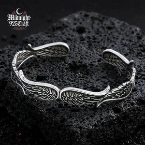 Detailed macro shot of the wing feather engraving on the 925 sterling silver cuff bracelet. The oxidized grooves between each feather line add depth and dimension, showcasing the handmade quality and Thai silver crafting technique. A distinctive piece for gothic or vintage jewelry lovers.
