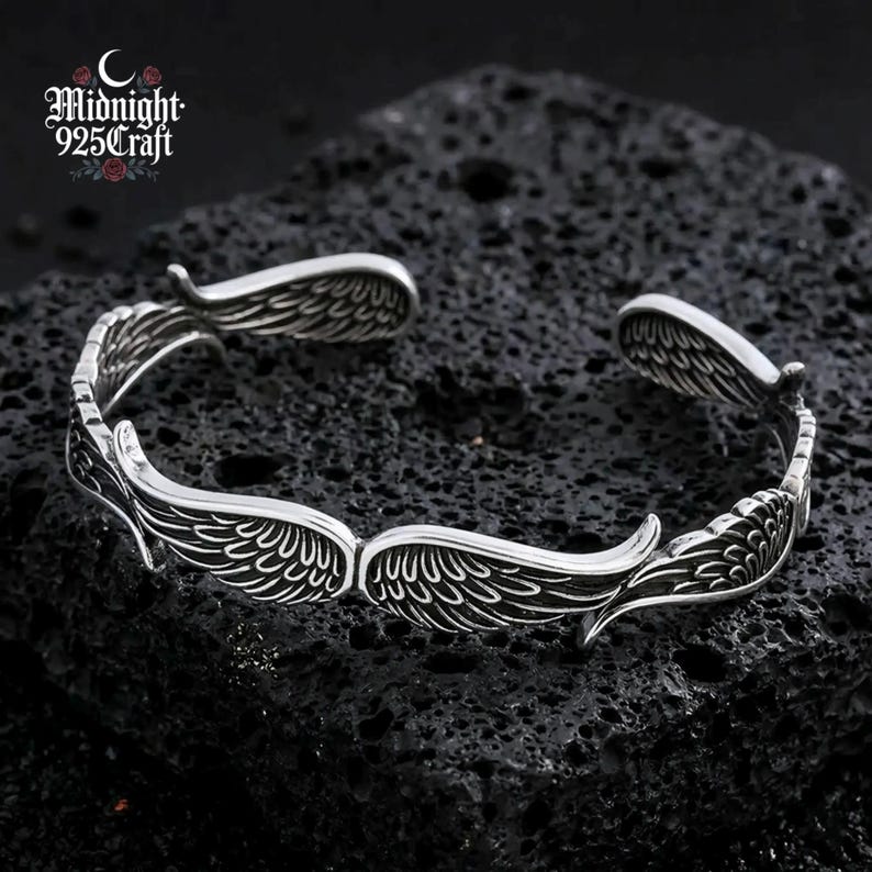 Detailed macro shot of the wing feather engraving on the 925 sterling silver cuff bracelet. The oxidized grooves between each feather line add depth and dimension, showcasing the handmade quality and Thai silver crafting technique. A distinctive piece for gothic or vintage jewelry lovers.