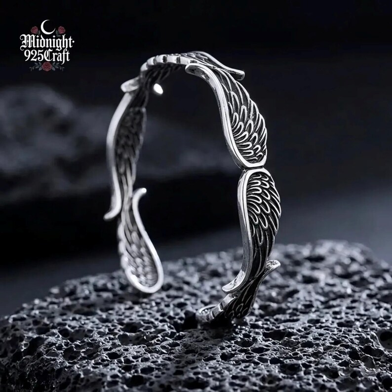 Full product showcase of the Angel Wings 925 Sterling Silver cuff bracelet against a dark textured background with the Midnight 925 Craft brand logo visible. The bracelet represents gothic, vintage, and boho jewelry styles, crafted as a hypoallergenic, skin-safe, tarnish-resistant silver piece.