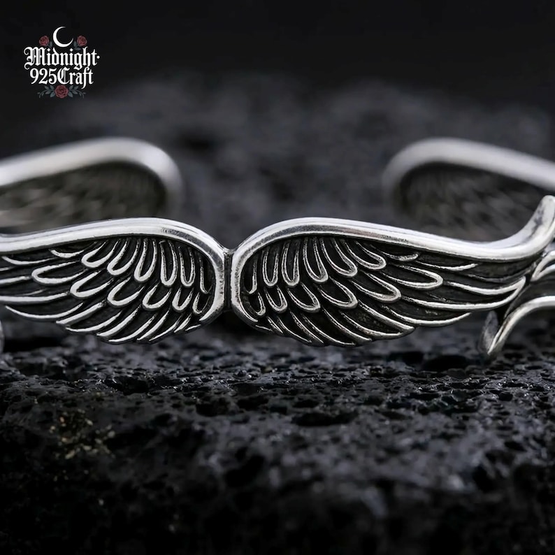 Top-down view of the Angel Wings 925 sterling silver bracelet showing paired wing motifs meeting at the center of the cuff. The intricate feather engraving detail reflects light beautifully, showcasing its artisanal quality. Suitable as a memorial bracelet, guardian angel gift, or couple matching jewelry.
