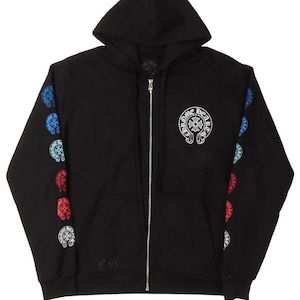 May include: A black zip-up hoodie featuring a white circular Chrome Hearts logo on the left chest. The sleeves are decorated with a vertical row of five small circular logos in alternating blue, light blue, and red colors. It has a silver zipper.