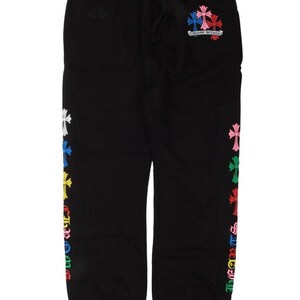 Op de afbeelding: Zwarte joggingbroek met een trekkoord in de taille en kleurrijke kruisontwerpen geborduurd op de zijkant en achterkant. De kruisen zijn in verschillende kleuren, waaronder wit, blauw, roze en groen. De tekst "Chrome Hearts" is ook zichtbaar.