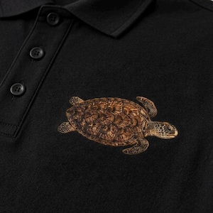 May include: A black polo shirt featuring a detailed brown sea turtle graphic embroidered on the chest. The shirt includes a classic collar and a buttoned placket with three matching black buttons, showcasing a textured fabric construction throughout.