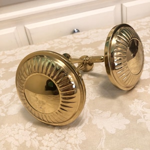 May include: A pair of gold metal curtain rod finials with a decorative sunburst design.