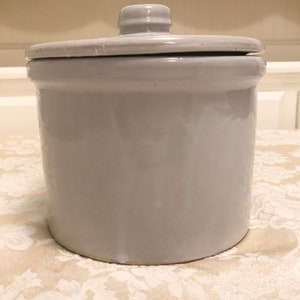 May include: A white ceramic crock with a lid. The crock is glazed and has a smooth finish.