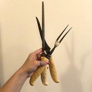 May include: Three antique kitchen knives with bone handles. The knives have ornate designs on the handles and are made of metal.