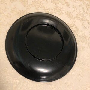 May include: A black lacquer tray with a raised rim and a smooth, glossy finish. The tray is circular and has a smaller, circular inset in the center.