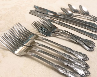 May include: A set of silverware with ornate handles. The set includes forks, knives, and spoons. The silverware is made of stainless steel and has a polished finish.