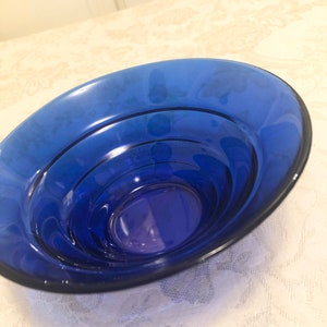 May include: A cobalt blue glass bowl with a layered design. The bowl is round and has a smooth, glossy finish.