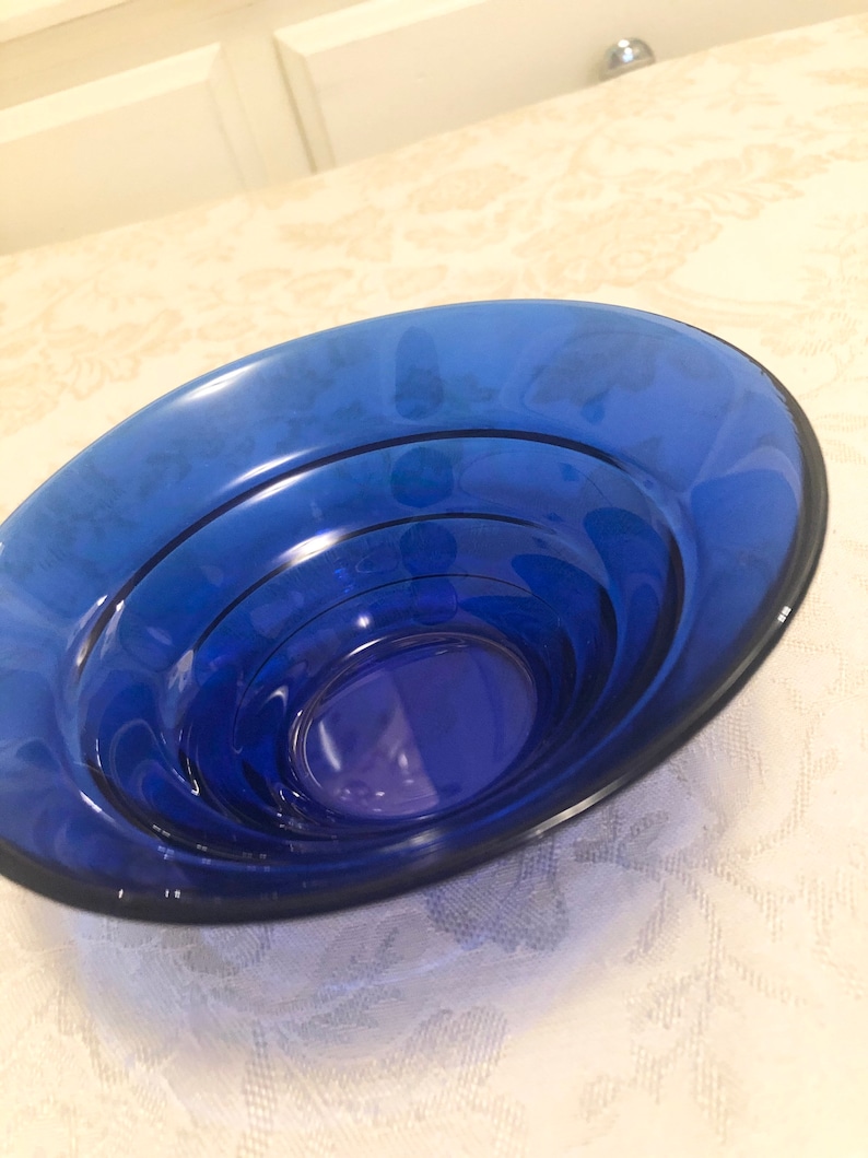 May include: A cobalt blue glass bowl with a layered design. The bowl is round and has a smooth, glossy finish.