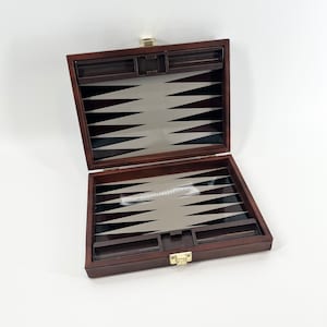 May include: A wooden backgammon game set with a brown exterior and a silver and black playing surface. The game is open and ready to play.