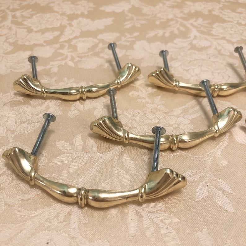 Puede incluir: Cinco tiradores de caj&oacute;n de armario de color dorado con un dise&ntilde;o decorativo y acanalado. Cada tirador tiene un solo tornillo para la instalaci&oacute;n.
