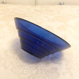 May include: A cobalt blue glass bowl with a fluted design. The bowl is made of thick glass and has a rounded shape.