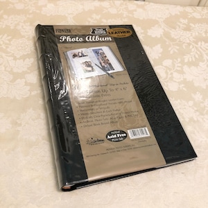May include: Black leather-bound photo album with a sewn European bonded leather cover. The album has a clear plastic pocket on the front cover that displays a sample photo. The album is acid-free and holds photos up to 4x6 inches. The album is made by Pioneer Photo Albums, Inc.