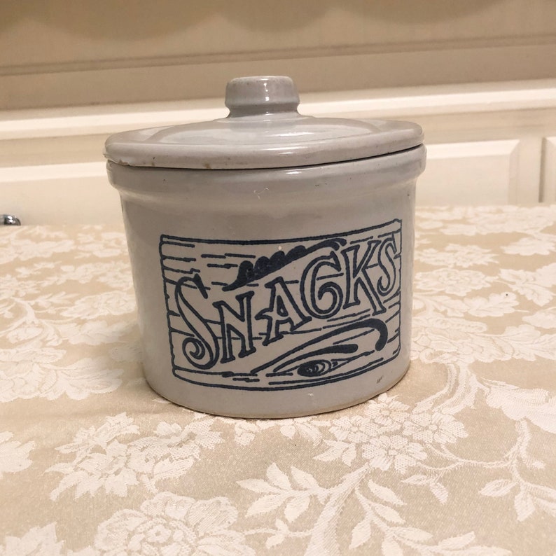 May include: A white ceramic jar with a blue lid and a blue design that says "SNACKS".