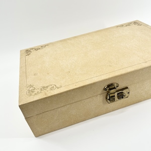 May include: A beige cardboard box with a decorative design and a metal latch. The box has a textured surface and a subtle sheen.