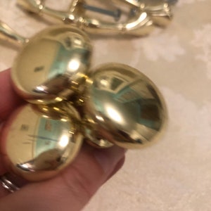 Puede incluir: Tres pomos redondos de armario de color dorado con un acabado brillante y reflectante.