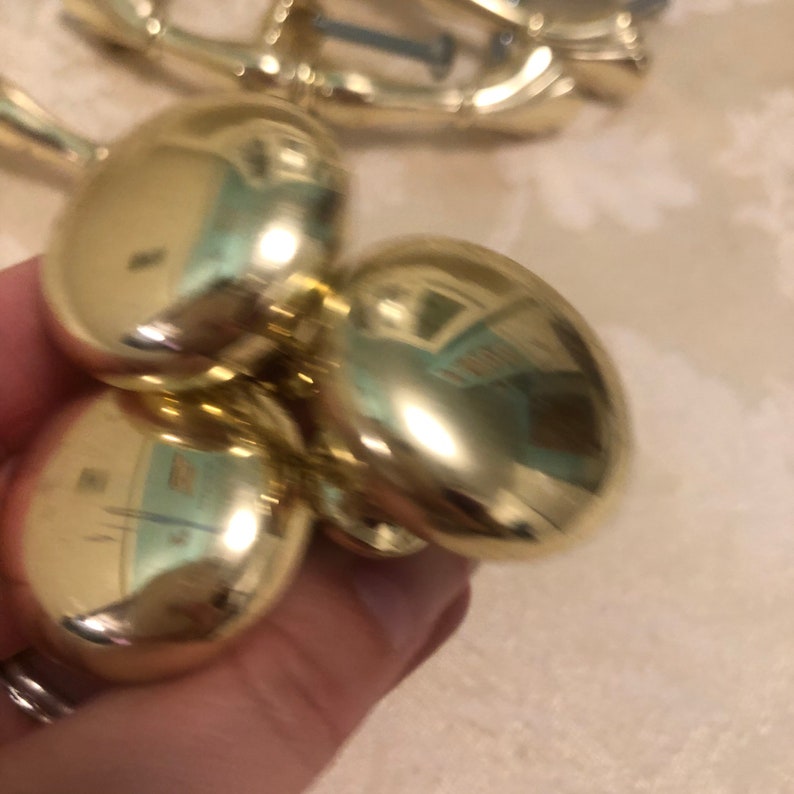 Puede incluir: Tres pomos redondos de armario de color dorado con un acabado brillante y reflectante.