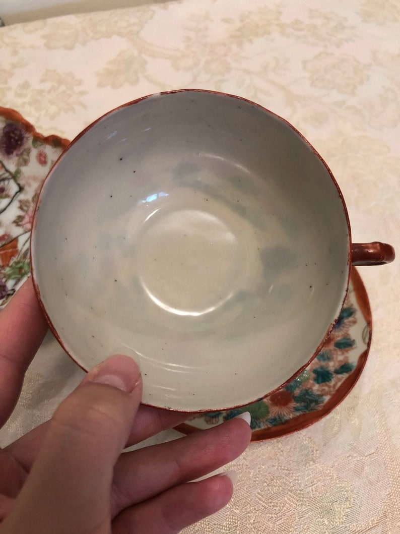 Antique Rose Medallion Chinese Lotus Nut Bowl And Tea Cups And Saucers Detailed In Gold And Red Trim Framing The Elegant Garden With Ladies
