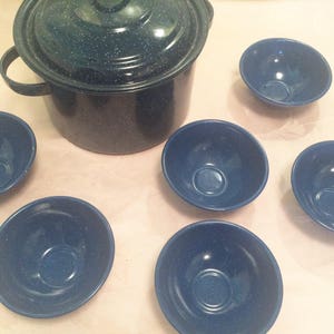 May include: A set of six blue enamel bowls and a blue enamel pot with a lid. The bowls are all the same size and have a white speckled design. The pot is larger than the bowls and has a white speckled design on the lid.