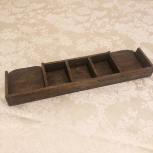 May include: A dark brown wooden tray with four compartments. The tray is empty and has a rustic look.
