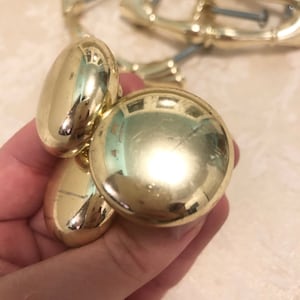 Puede incluir: Tres pomos de armario de color dorado con un dise&ntilde;o redondo y liso. Los pomos son de metal y tienen un acabado brillante.